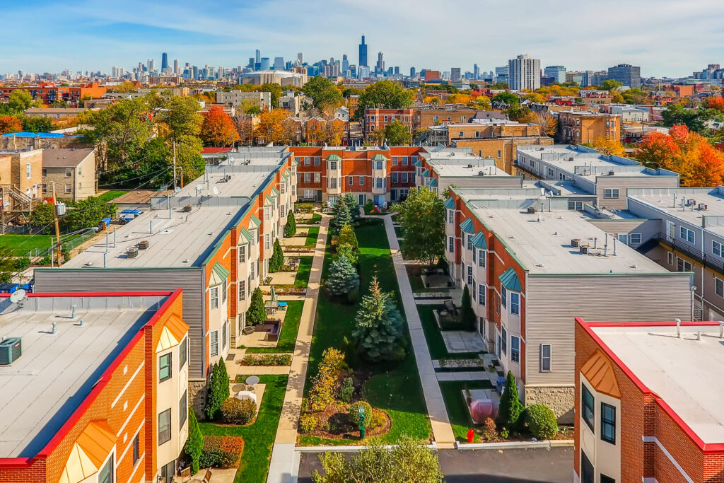 Aerial drone picture of multi-family townhome complex compared to it's location in a city. Showcases the property proximity to downtown. Image by Virtuance