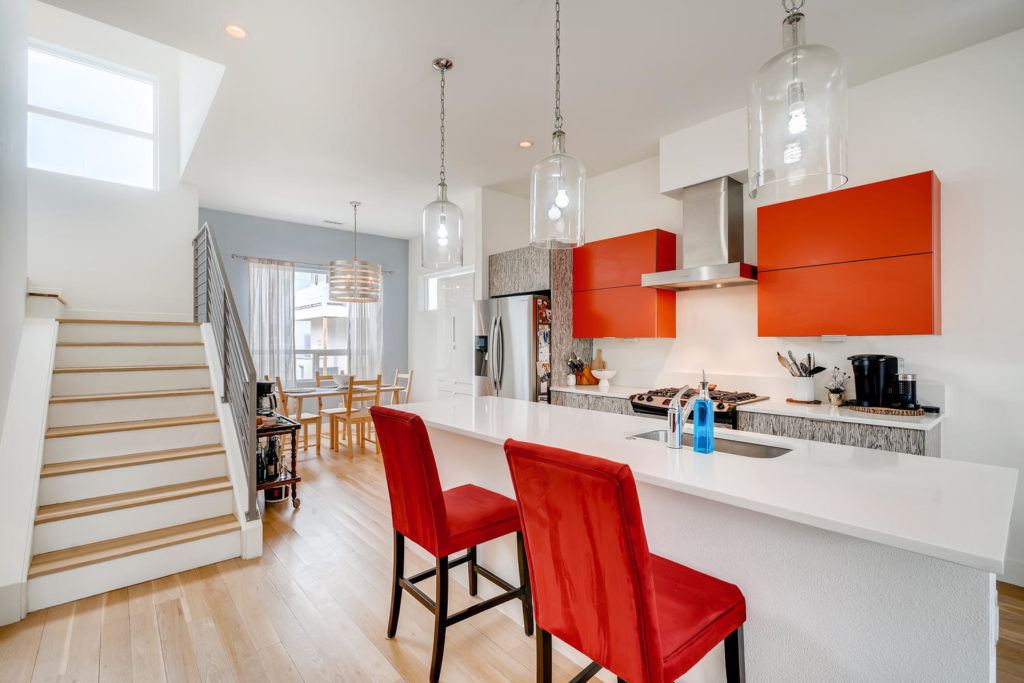 real estate image of kitchen with red chairs and cabinets