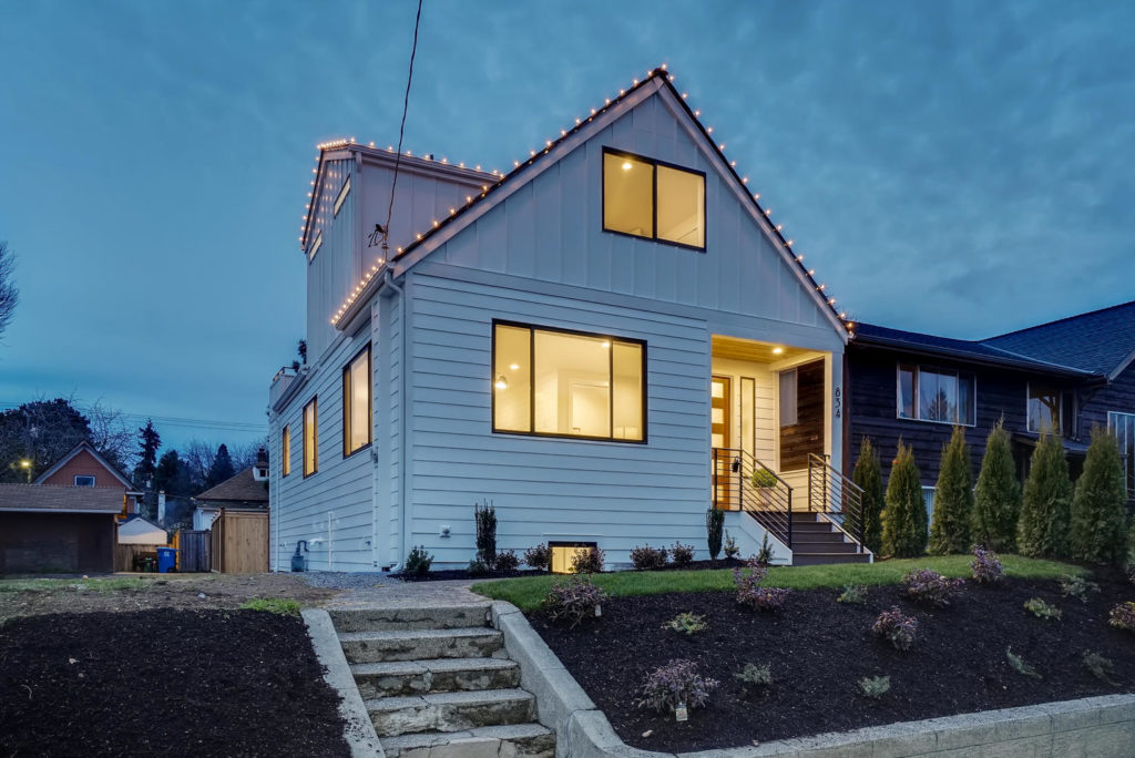 White home at twilight with string lights on roof