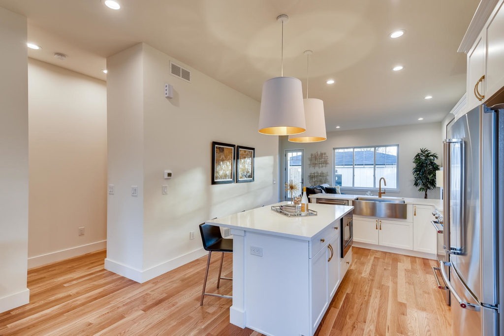 Kitchen with white island and large white pendant lights
