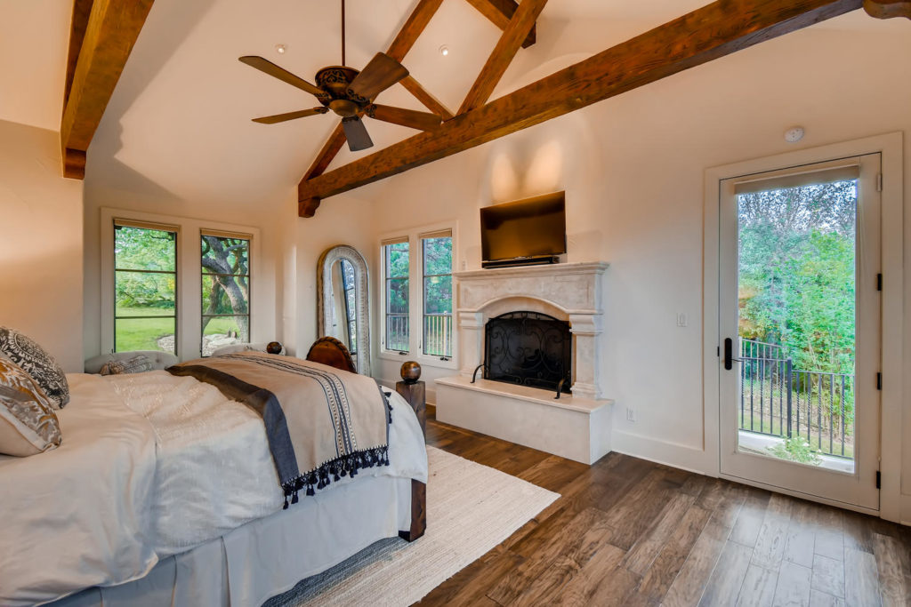 Master bedroom with fireplace and wood beams