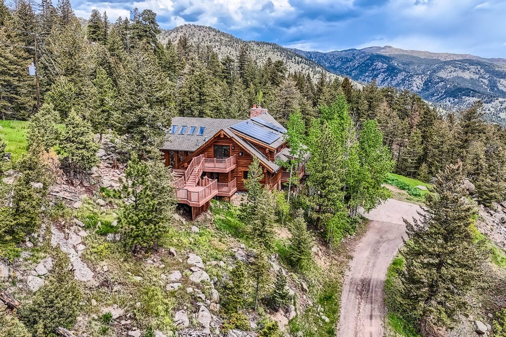 Aerial view of a log cabin style, mountain property showcasing how the home sits in the mountainside. Image captured by Virtuance
